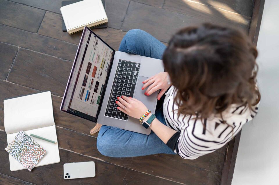 Digital marketing professional working on a MacBook laptop, viewed from overhead, surrounded by notebooks and a smartphone, representing small business online marketing services in Noblesville Indiana